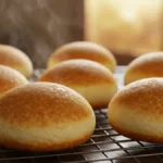 Petits pains au lait dorés refroidissant sur une grille après cuisson