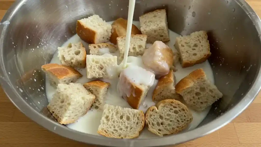 Cubes de pain rassis trempés dans du lait dans un saladier en inox