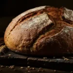 Pain de campagne artisanal sur planche en bois avec épis de blé