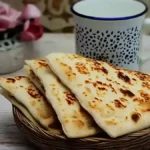 Kesra coupée en triangles servie dans un panier avec un verre de thé