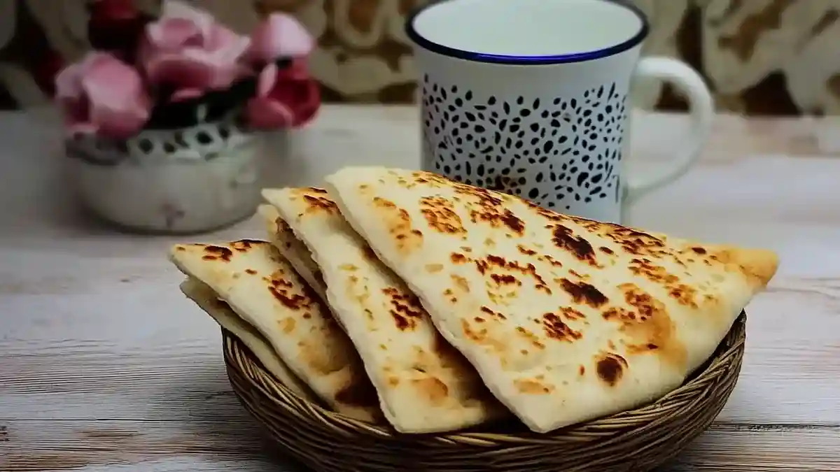 Kesra coupée en triangles servie dans un panier avec un verre de thé