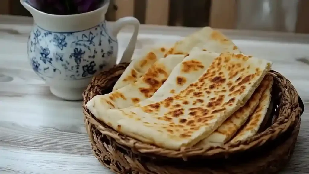Galettes de kesra dorées servies dans un panier tressé avec un pichet en céramique