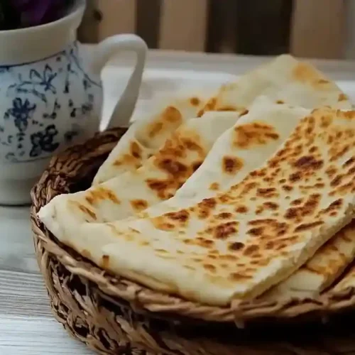 Galettes de kesra dorées servies dans un panier tressé avec un pichet en céramique