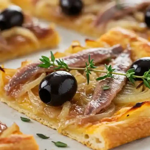 Tranche de pissaladière niçoise avec oignons confits, anchois, olives noires et thym frais.