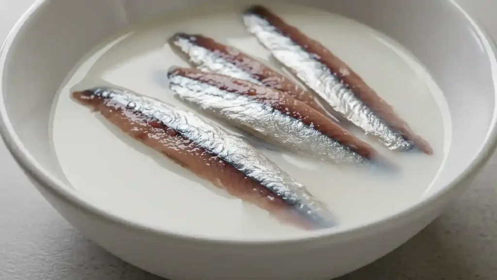 Filets d’anchois trempés dans un bol de lait pour adoucir leur goût salé.