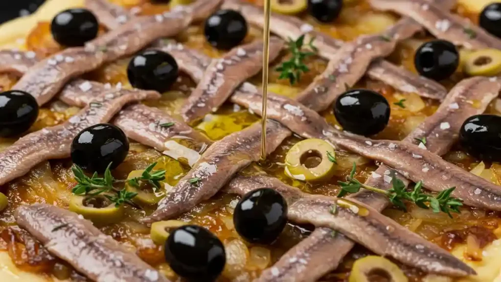 Pissaladière crue garnie d’anchois, olives noires, olives vertes et thym frais, arrosée d’un filet d’huile d’olive.