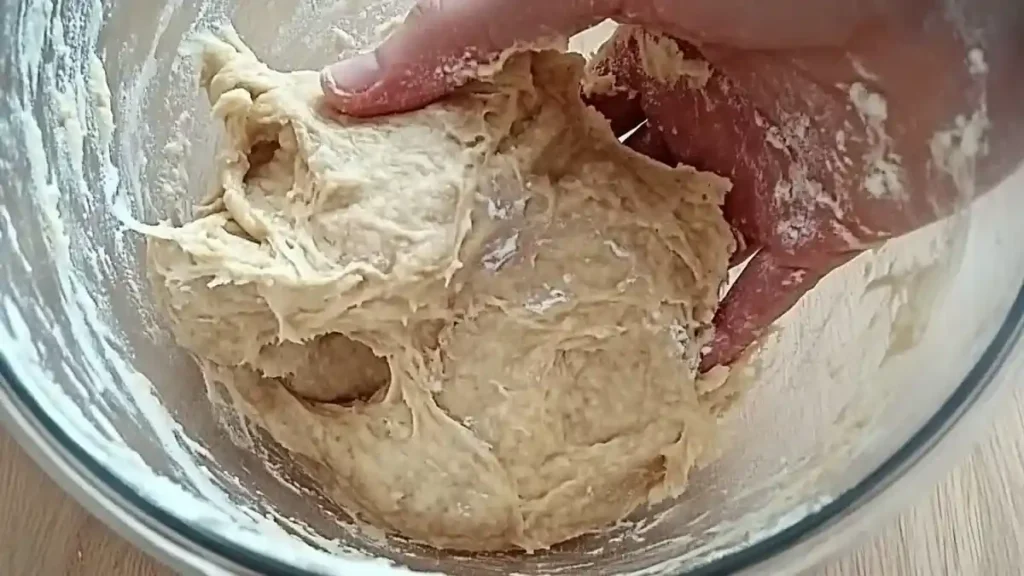 Main mélangeant une pâte à pain kebab collante dans un saladier
