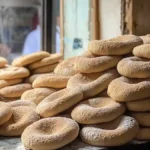 Pains khobz marocains empilés dans une boulangerie artisanale à proximité d’une fenêtre