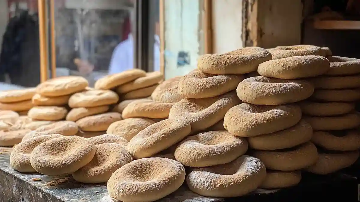 Pains khobz marocains empilés dans une boulangerie artisanale à proximité d’une fenêtre