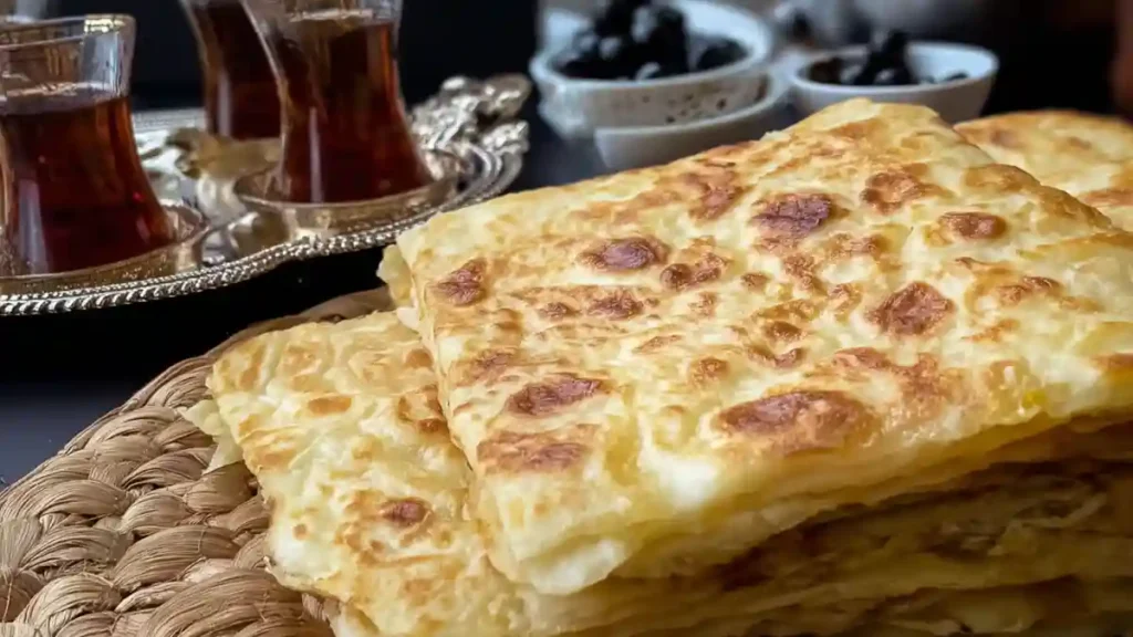 Pile de msemen marocains dorés, servis pour le petit-déjeuner avec thé et olives.