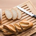 Planche à trancher avec couteau à pain et tranches de baguette et de pain rond