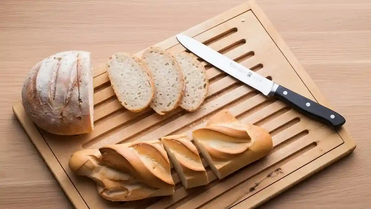Planche à trancher avec couteau à pain et tranches de baguette et de pain rond