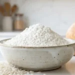Bol de farine de riz blanche avec grains de riz et pain sans gluten en arrière-plan