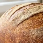 Pain à la semoule fine maison, rond et doré, posé sur un plan de travail clair