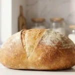 Pain sans sel maison à la croûte dorée posé sur un plan de travail clair