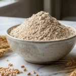 Farine de seigle dans un bol avec grains et épis de seigle