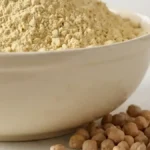 Bol de farine de pois chiches avec pois chiches secs dans une cuisine de boulangerie lumineuse.