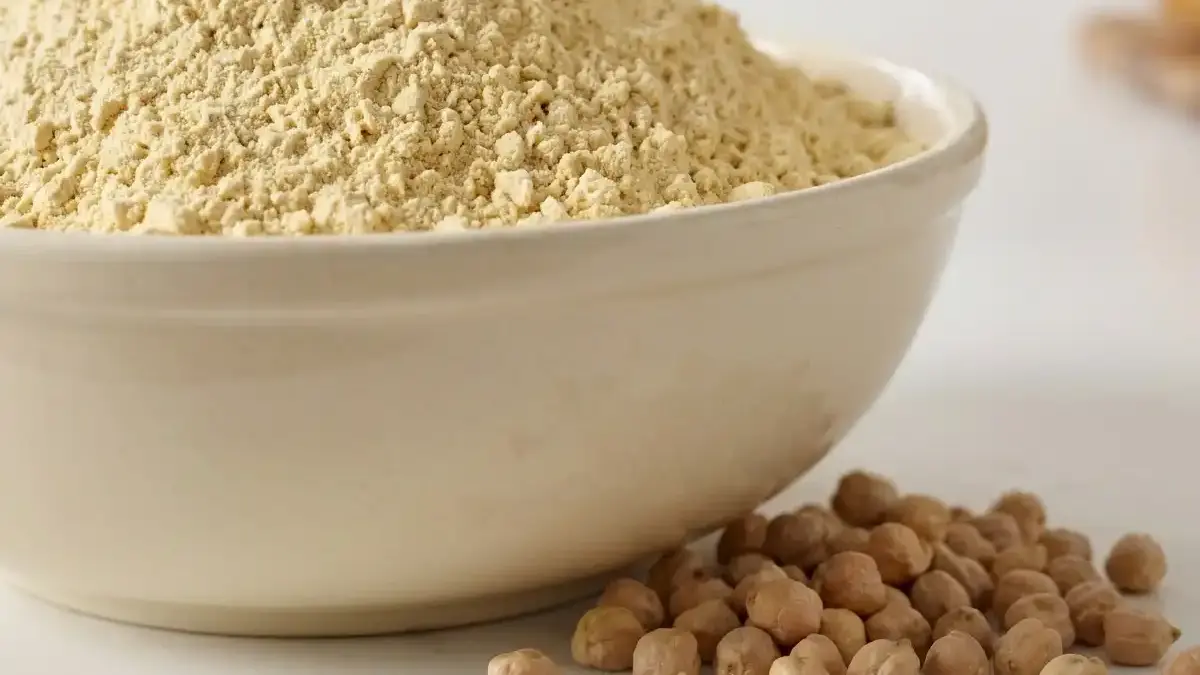Bol de farine de pois chiches avec pois chiches secs dans une cuisine de boulangerie lumineuse.