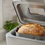 Machine à pain ouverte avec un pain maison doré fraîchement cuit dans la cuve.